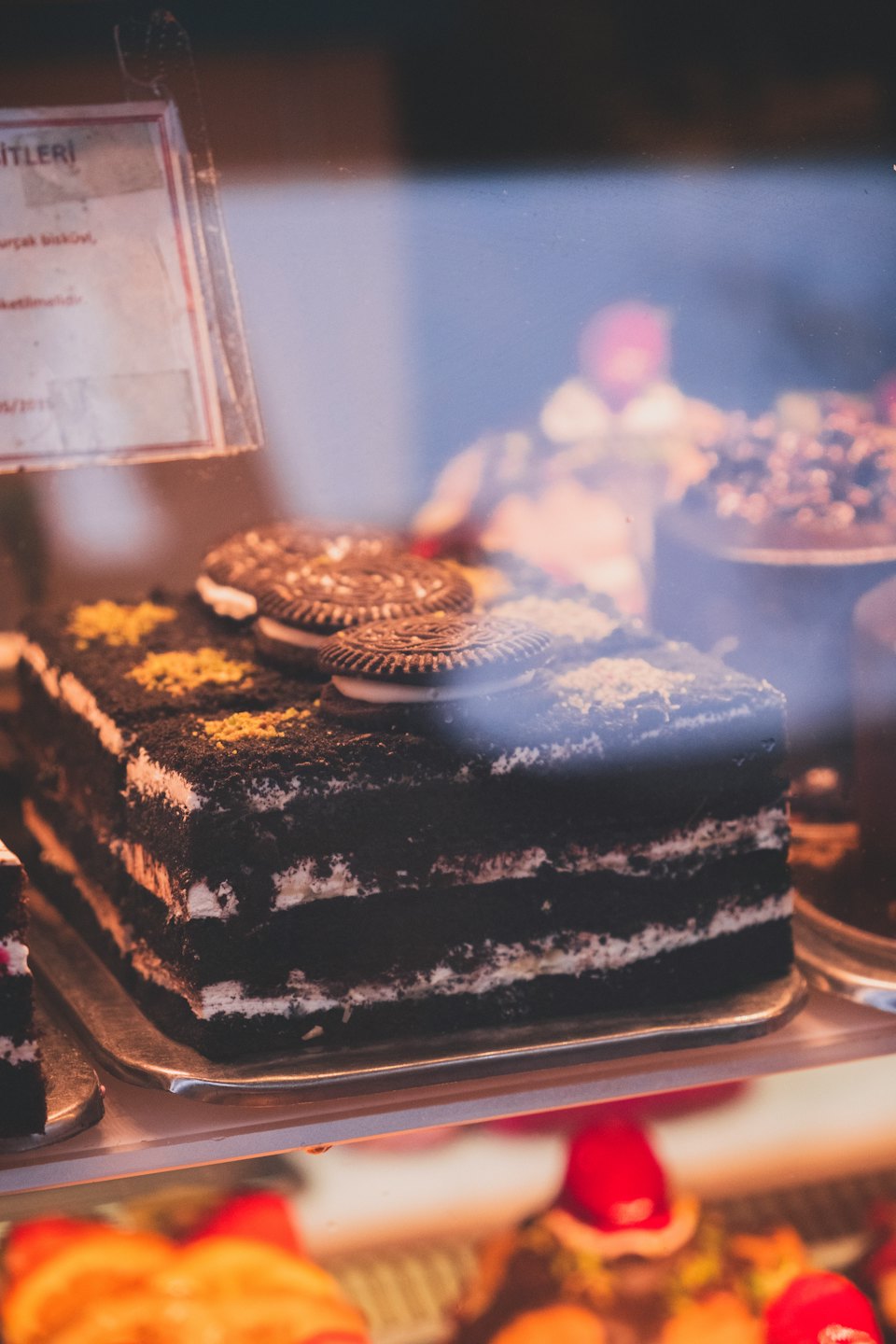 Layered chocolate cake with cookie topping sits on a tray.