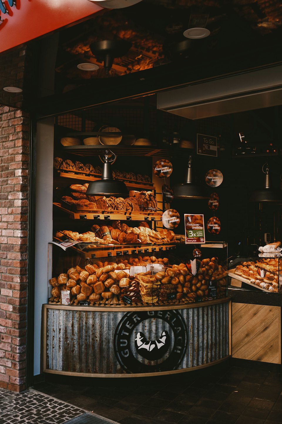 Fresh breads and pastries displayed on rustic wooden shelves.