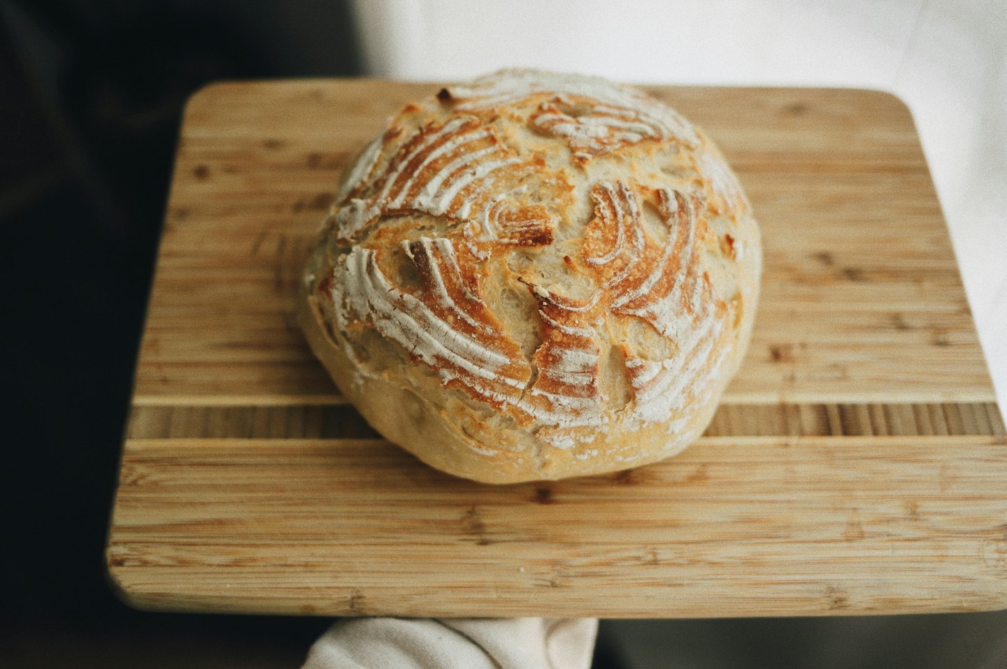 A round loaf of artisan bread sits on a wooden board.