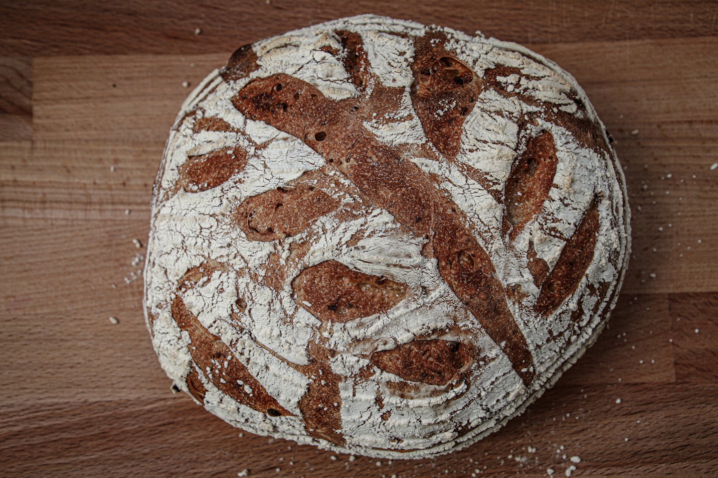 Artisan sourdough loaf with scoring marks on a wooden board.