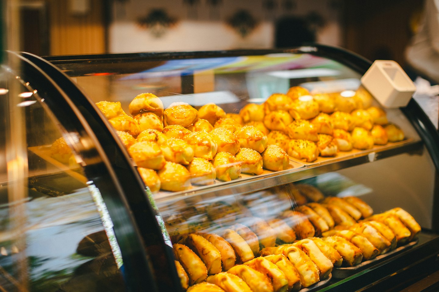 Fresh pastries and rolls sit on shelves in a display case.